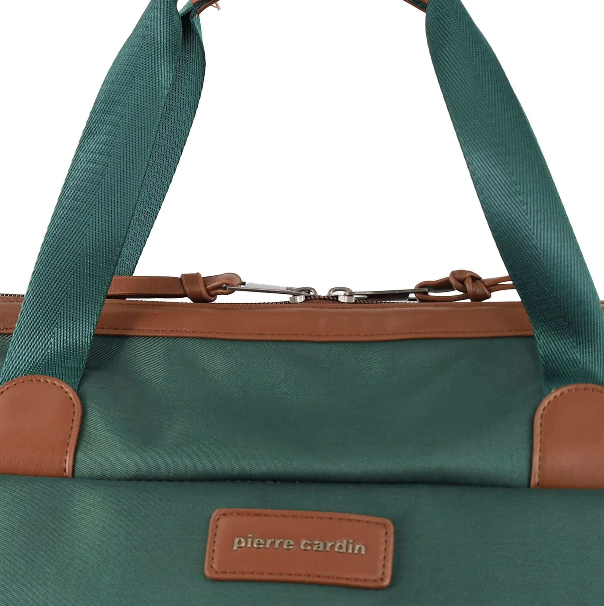 Close-up of a Pierre Cardin duffel bag in dark green nylon with tan leather trim, handles, and a brand patch on a brown leather background.